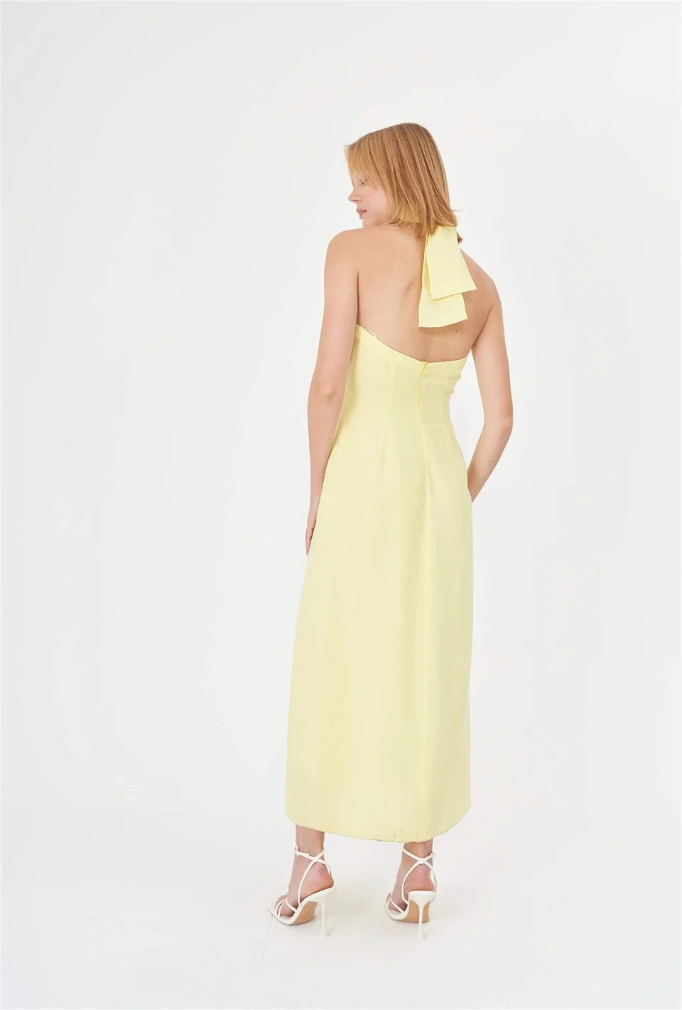 A stunning yellow summer dress featuring a halter neck design, made from lightweight bio-based and organic fabric. This dress adds a vibrant pop of color to your wardrobe and is suitable for various summer occasions such as beach outings, pool parties, gatherings, and street style looks.